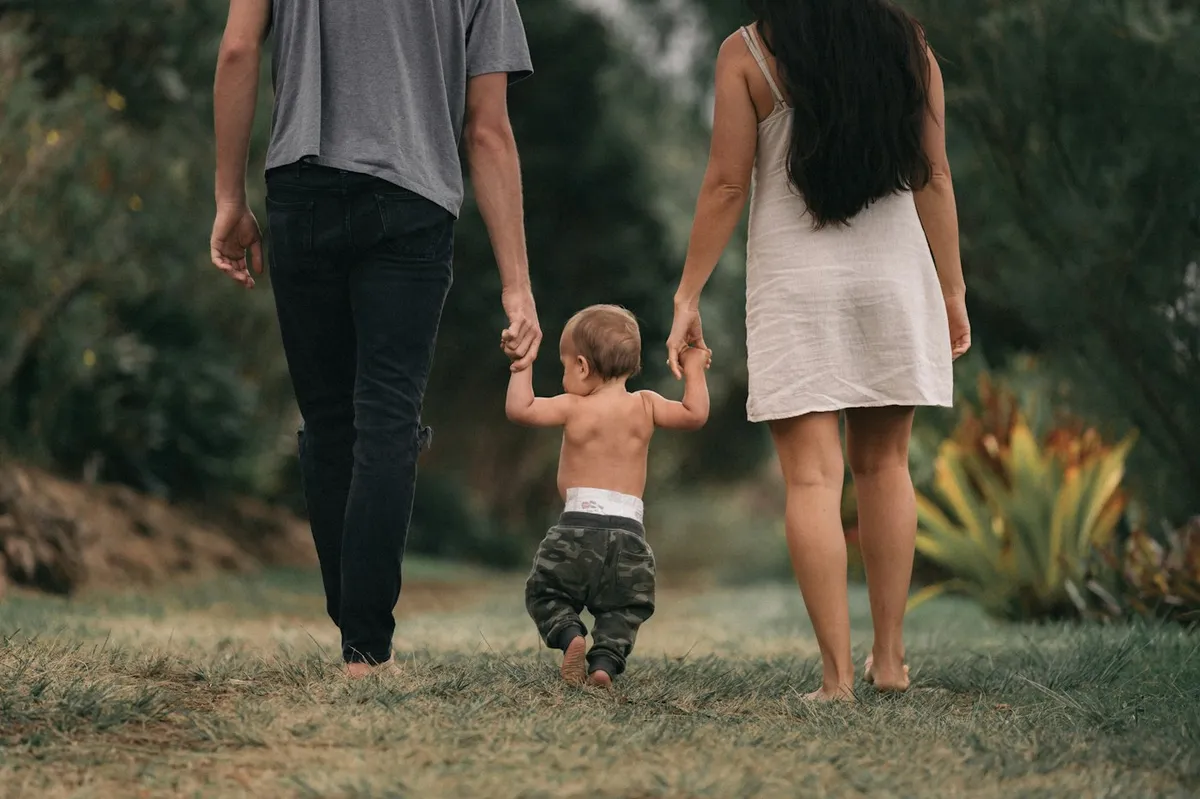 Un couple et son enfant marchent dans leur jardin
